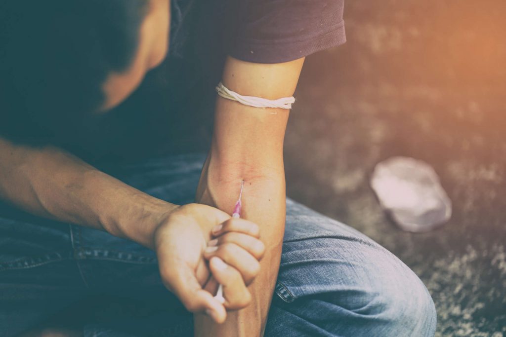 Person injecting intravenous drugs into forearm